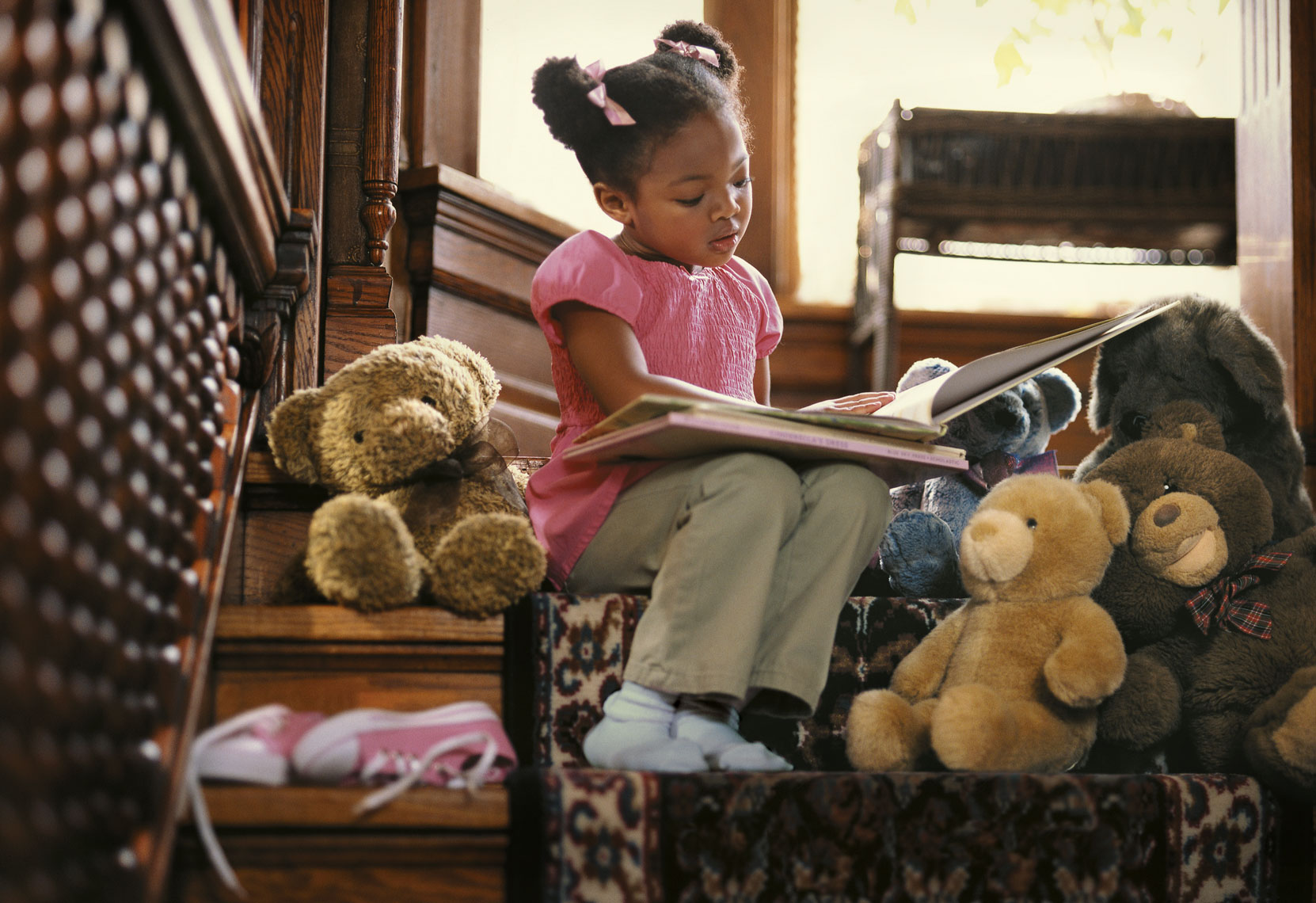 Environmental portrait of a young African American girl reading books for an advertising campaign